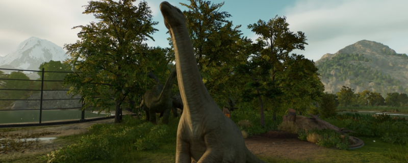 《侏罗纪世界：进化3》游戏界面截图：蔚蓝泻湖中鱼龙轻盈游弋，远处沧龙巨尾缓缓摆动，水面泛起层层波纹，背景可见公园观景栈道与科研监测塔