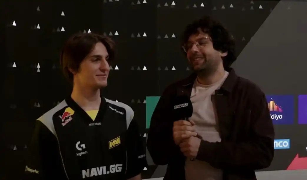 赛后采访现场图：NAVI队员围坐接受媒体提问，Riddys手持麦克风神情沉稳，身后电子屏显示‘NAVI 2-0 XG’战绩